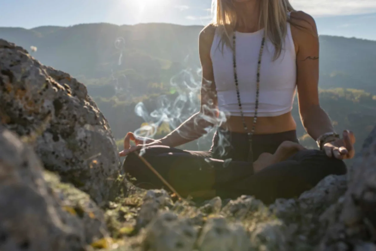 woman meditating on top of cliff